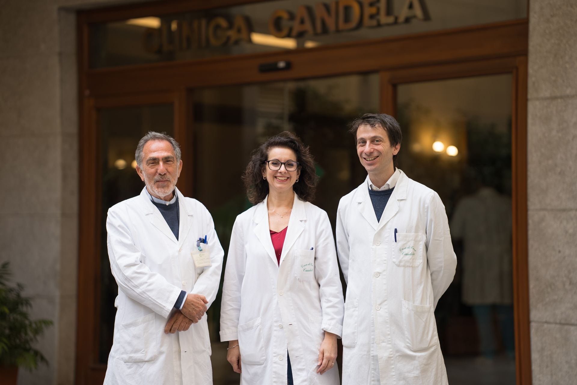 Tre dottori posano per una foto davanti a un edificio.