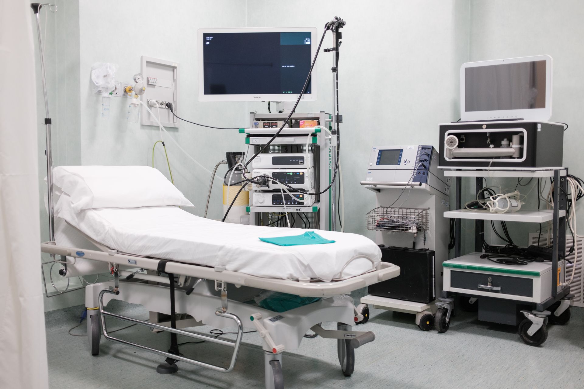 Una stanza d'ospedale con un letto, monitor e altre apparecchiature mediche.