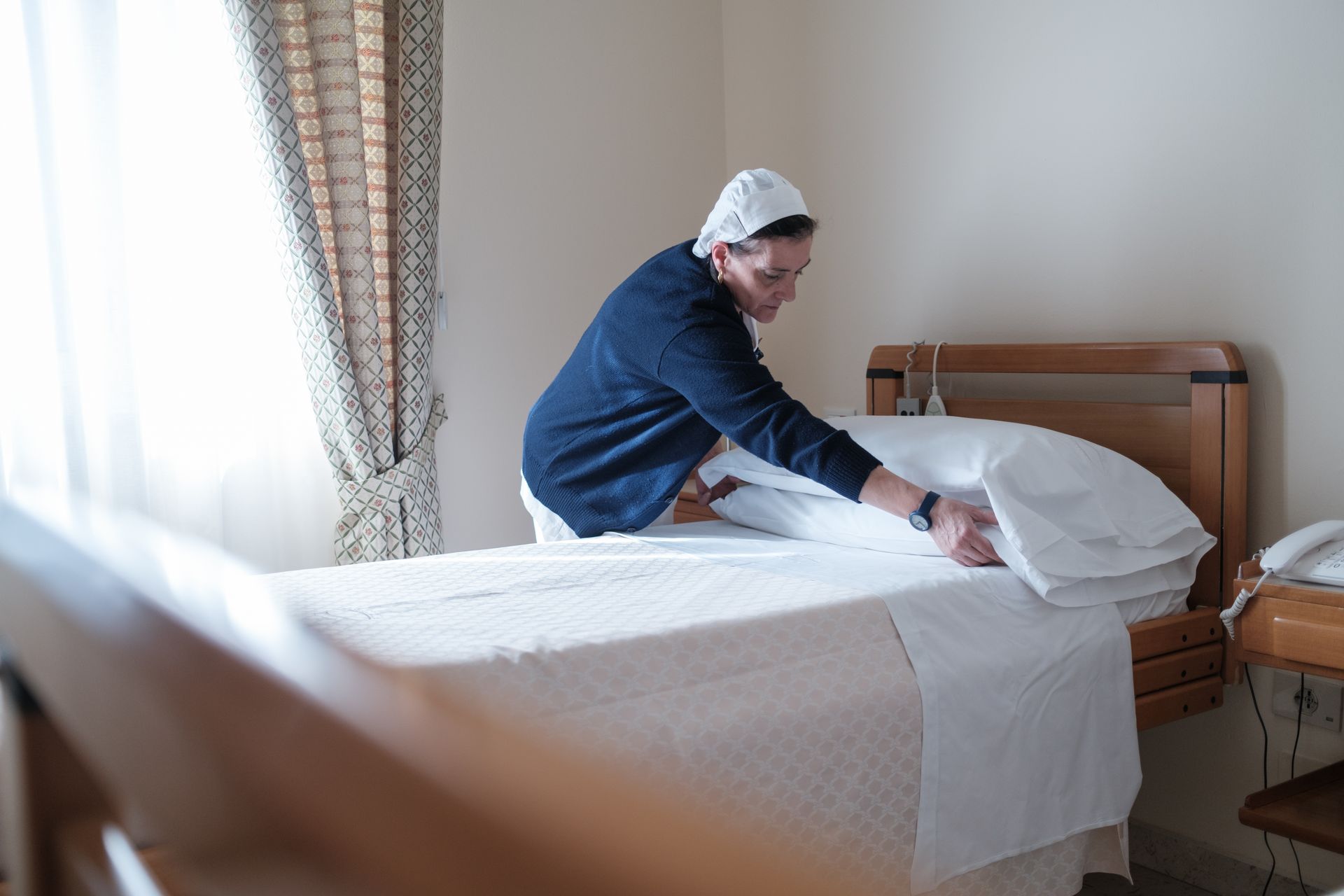 Una donna sta rifacendo il letto in una stanza d'albergo