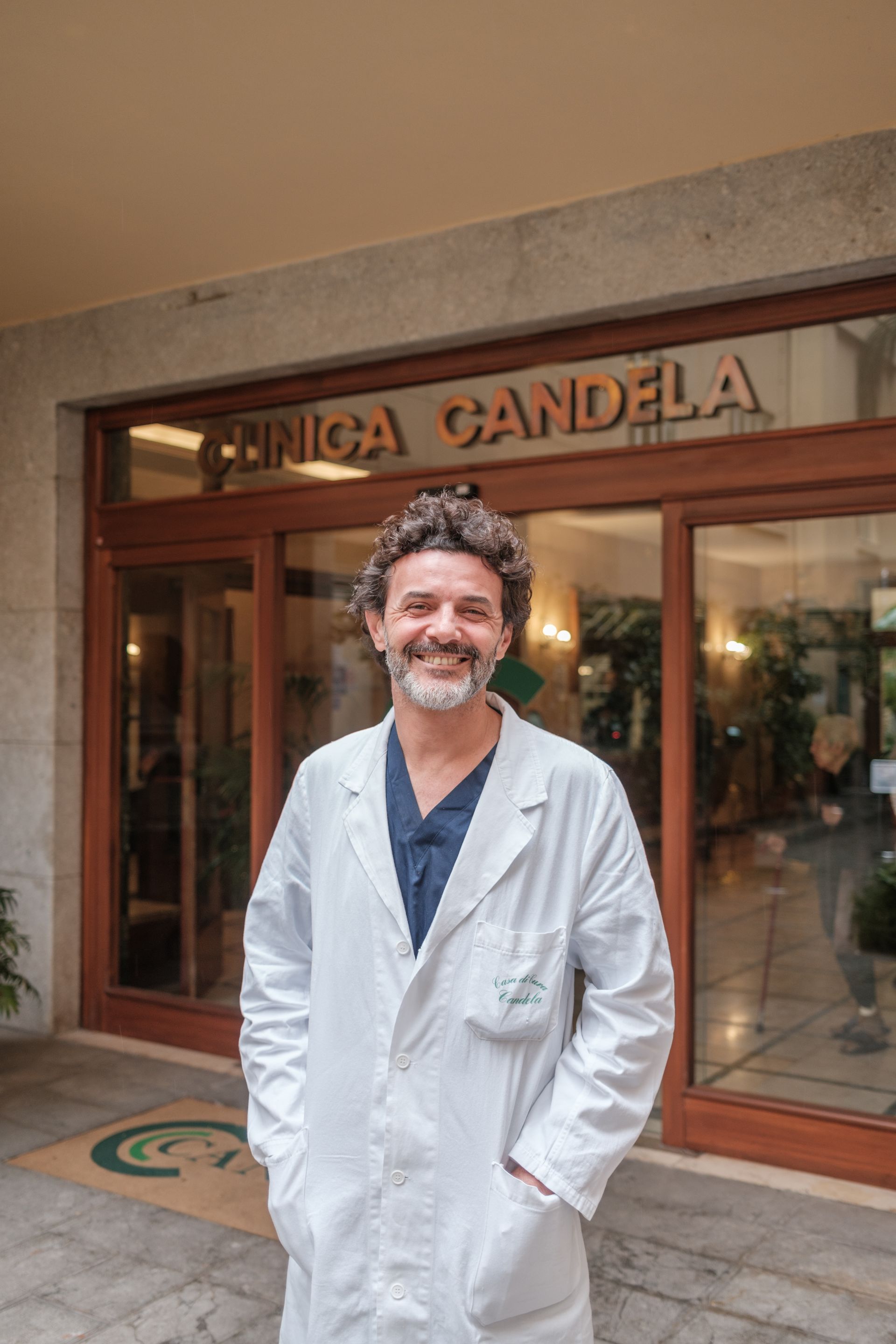 Un uomo in camice è in piedi davanti a un edificio.