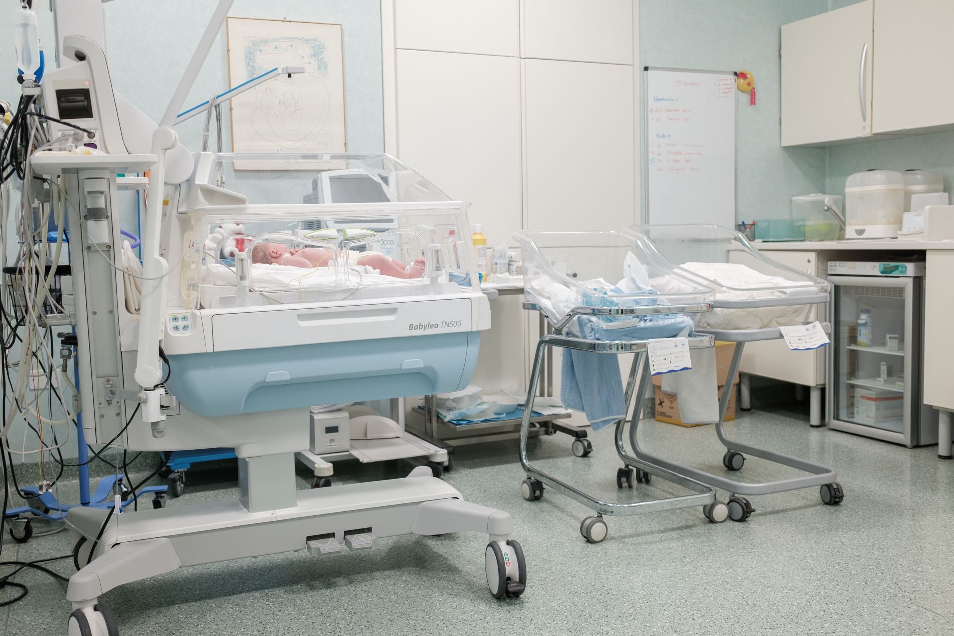 Una stanza d'ospedale con un neonato in un'incubatrice.
