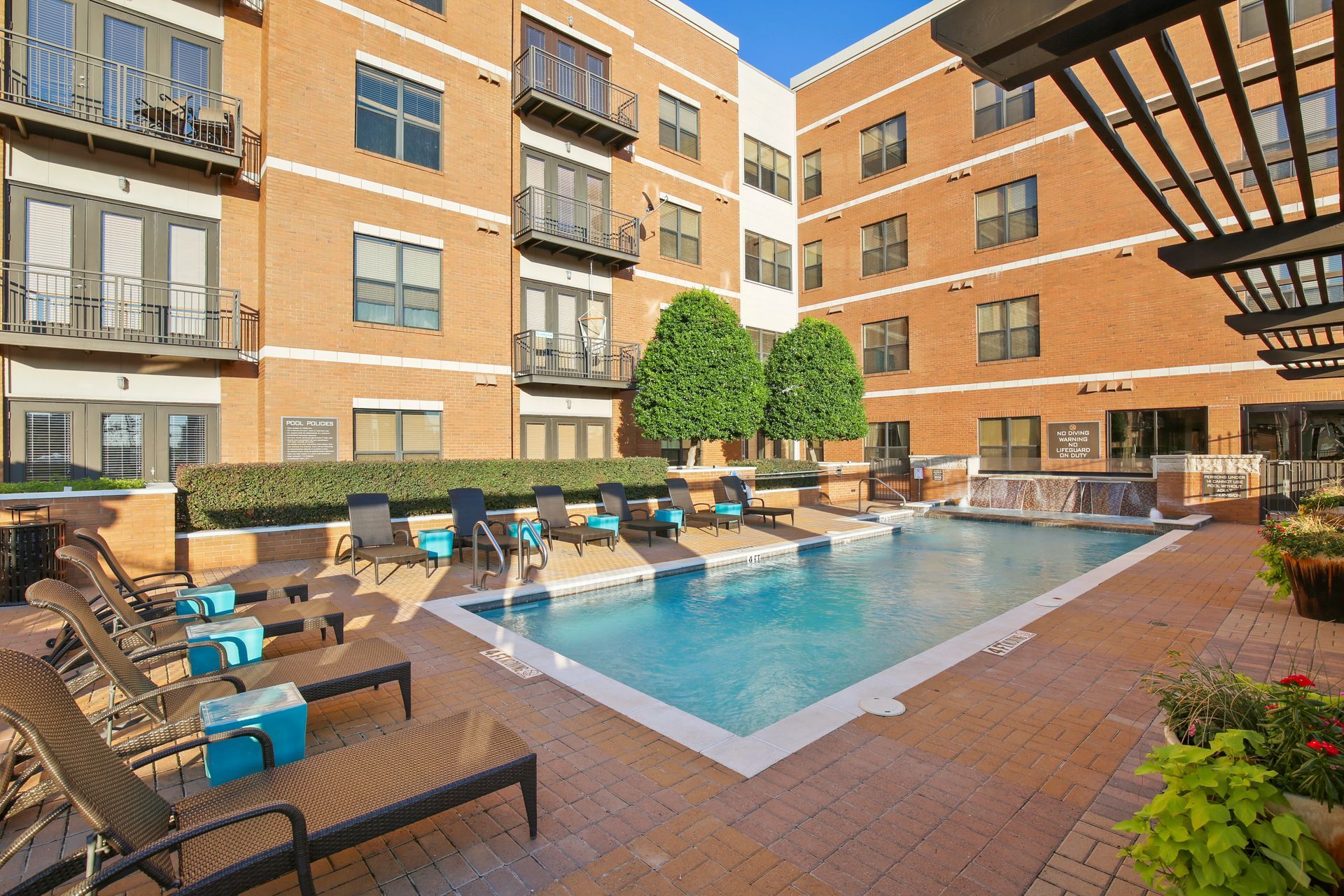 A large swimming pool is in the middle of a large apartment building.