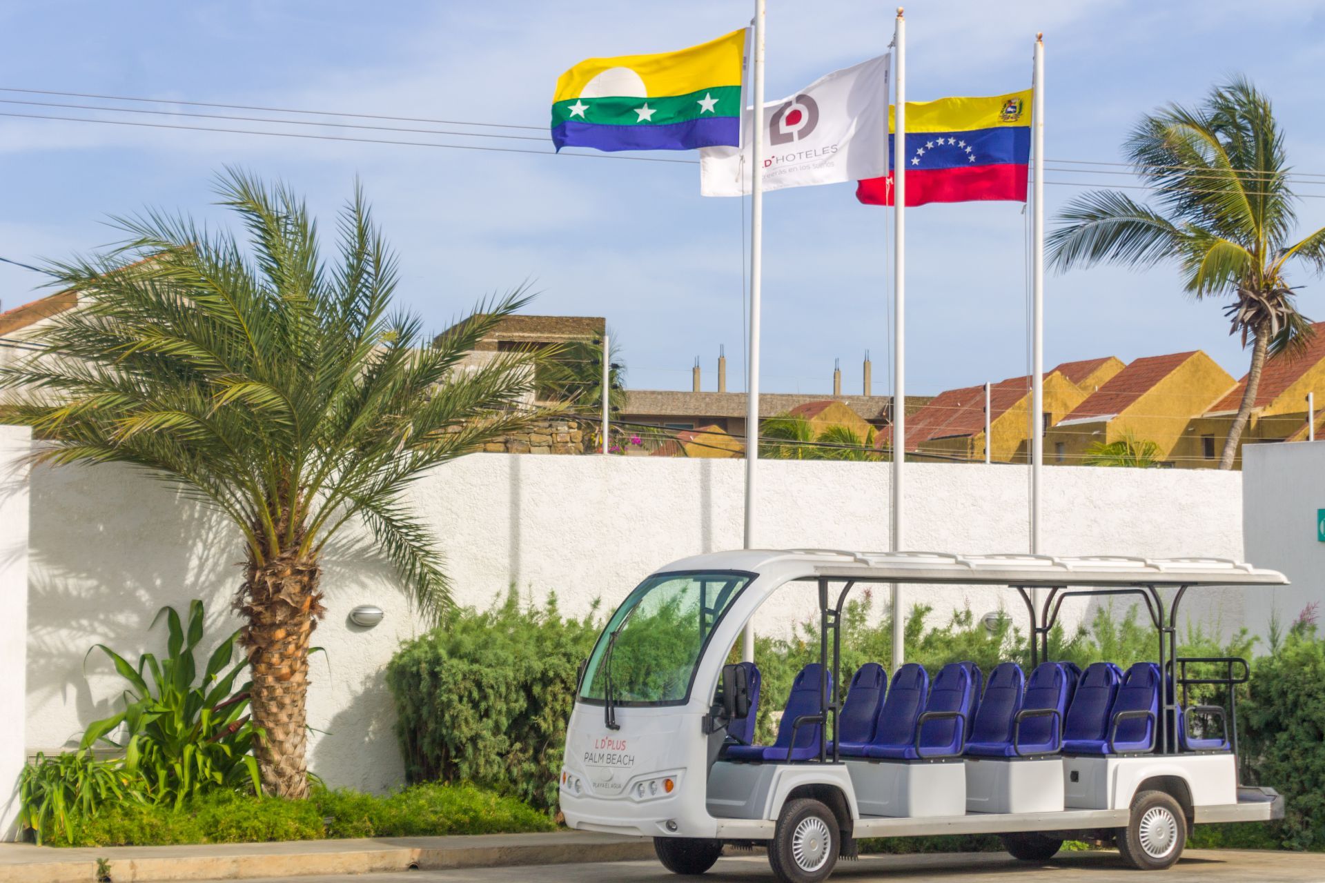 Carrito eléctrico LD PLUS blanco con asientos azules para transporte de huéspedes a la playa.