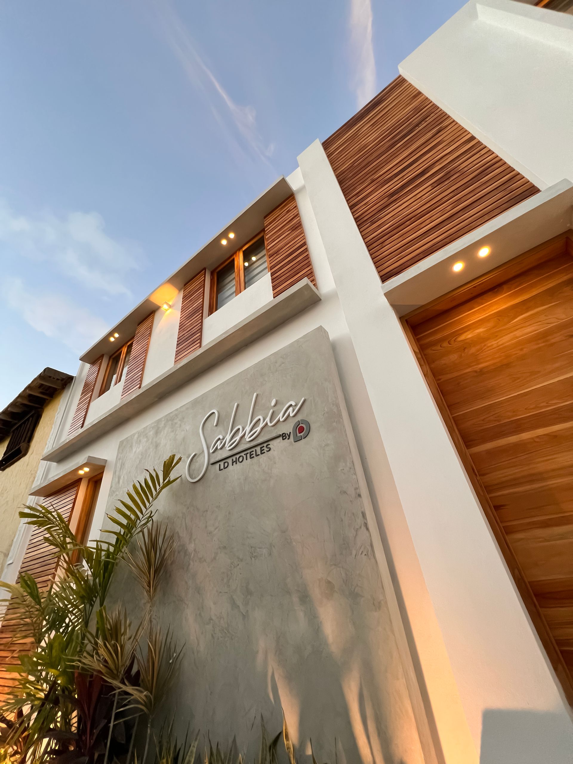 Fachada de ‘Sabbia by LD’ Hoteles en Los Roques, con diseño moderno y elementos de madera, capturada al atardecer.