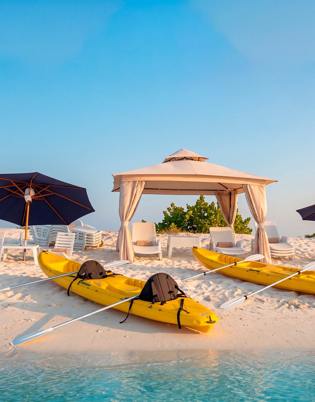 Kayak en Los Roques, disfrutando de actividades acuáticas en una playa soleada con instalaciones recreativas.