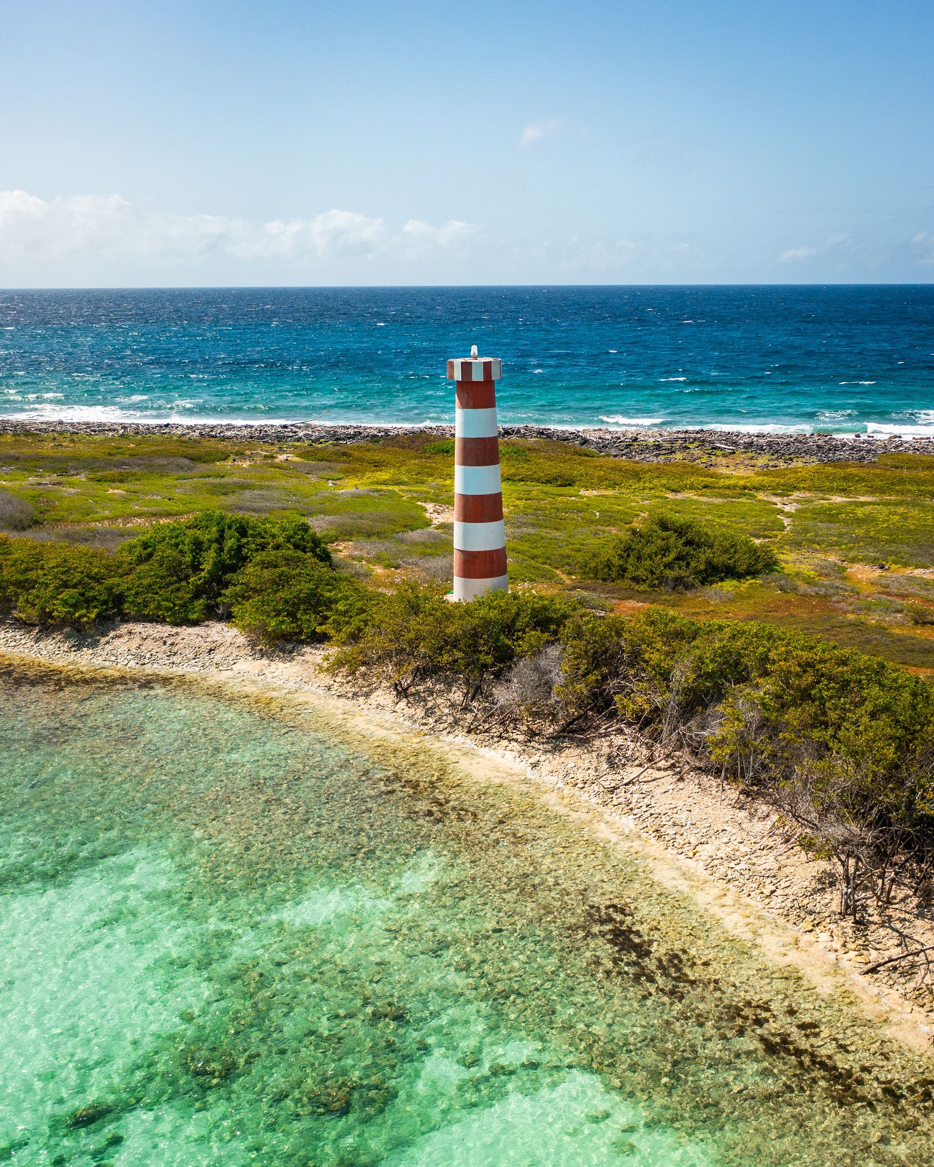 Faro el Holandés en Los Roques, un faro histórico en un paisaje rocoso con vistas al mar y cielo despejado.