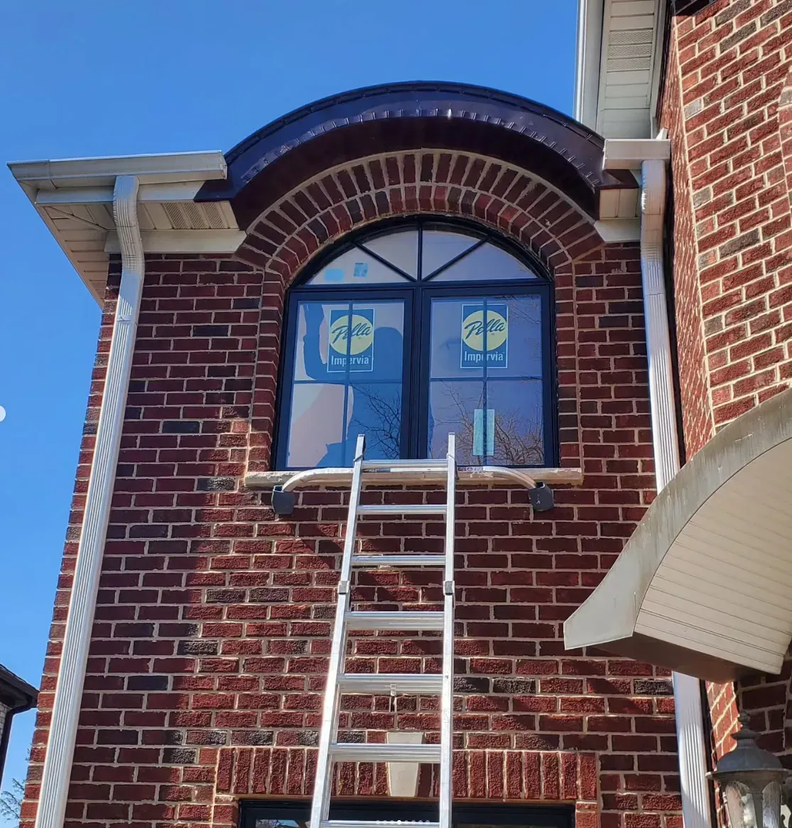 Brick building exterior with arched window and ladder leaning up to the sill