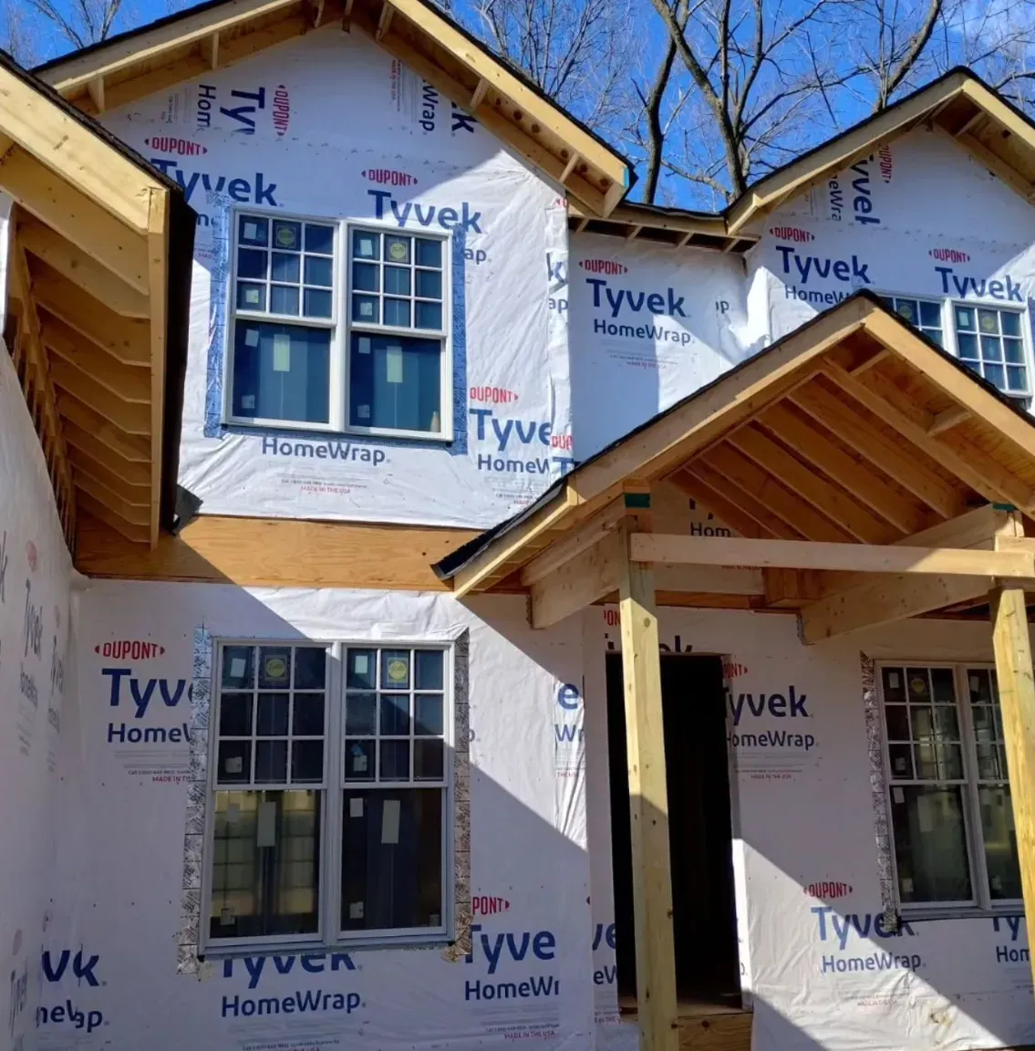 New homes under construction with Tyvek wrap and exposed wooden roof framing