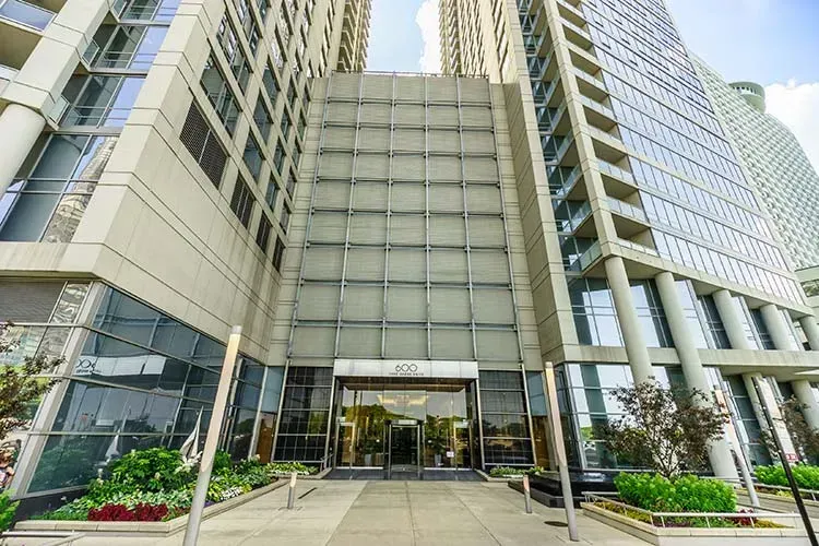 Modern office building entrance with glass facade, columns, and landscaped planters