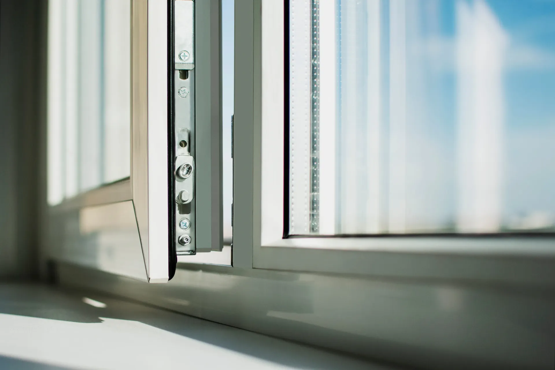 Close-up of a sunlit white window frame and sill with soft blue light outside