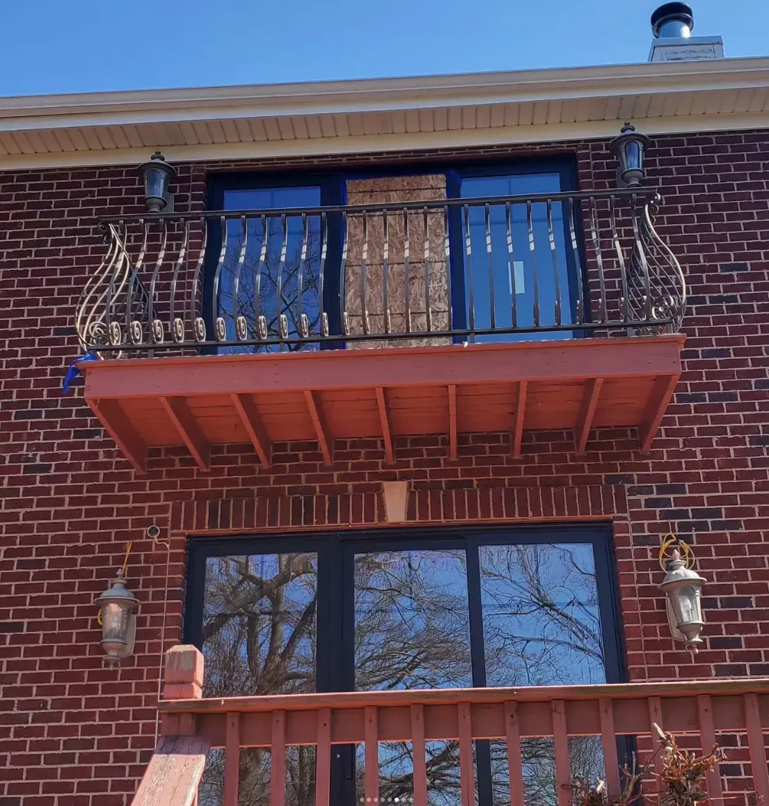 Red brick apartment building with a small wrought-iron balcony and a large window below