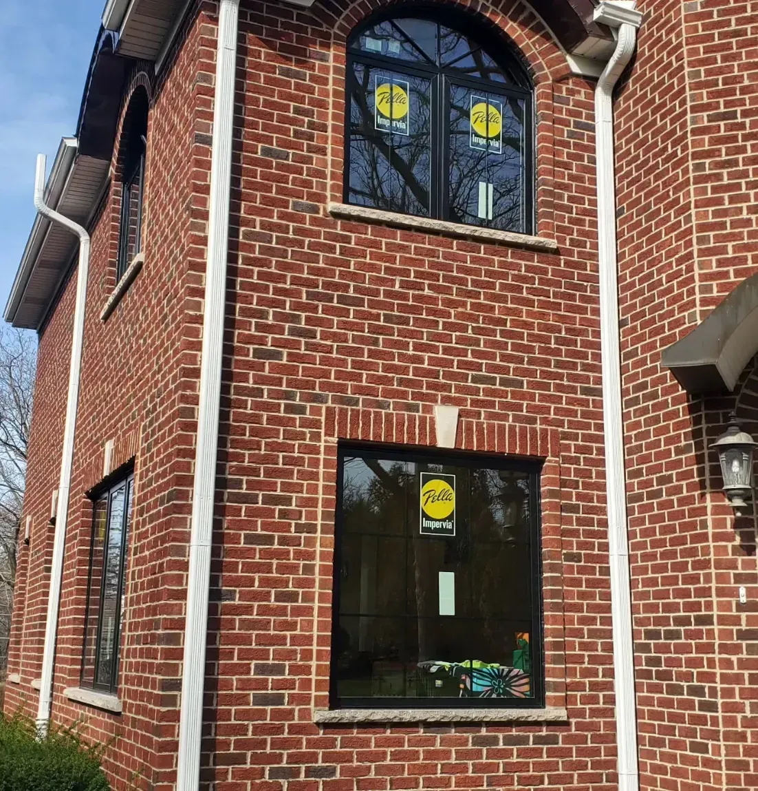Brick building corner with black-trimmed windows and a wall-mounted lantern.