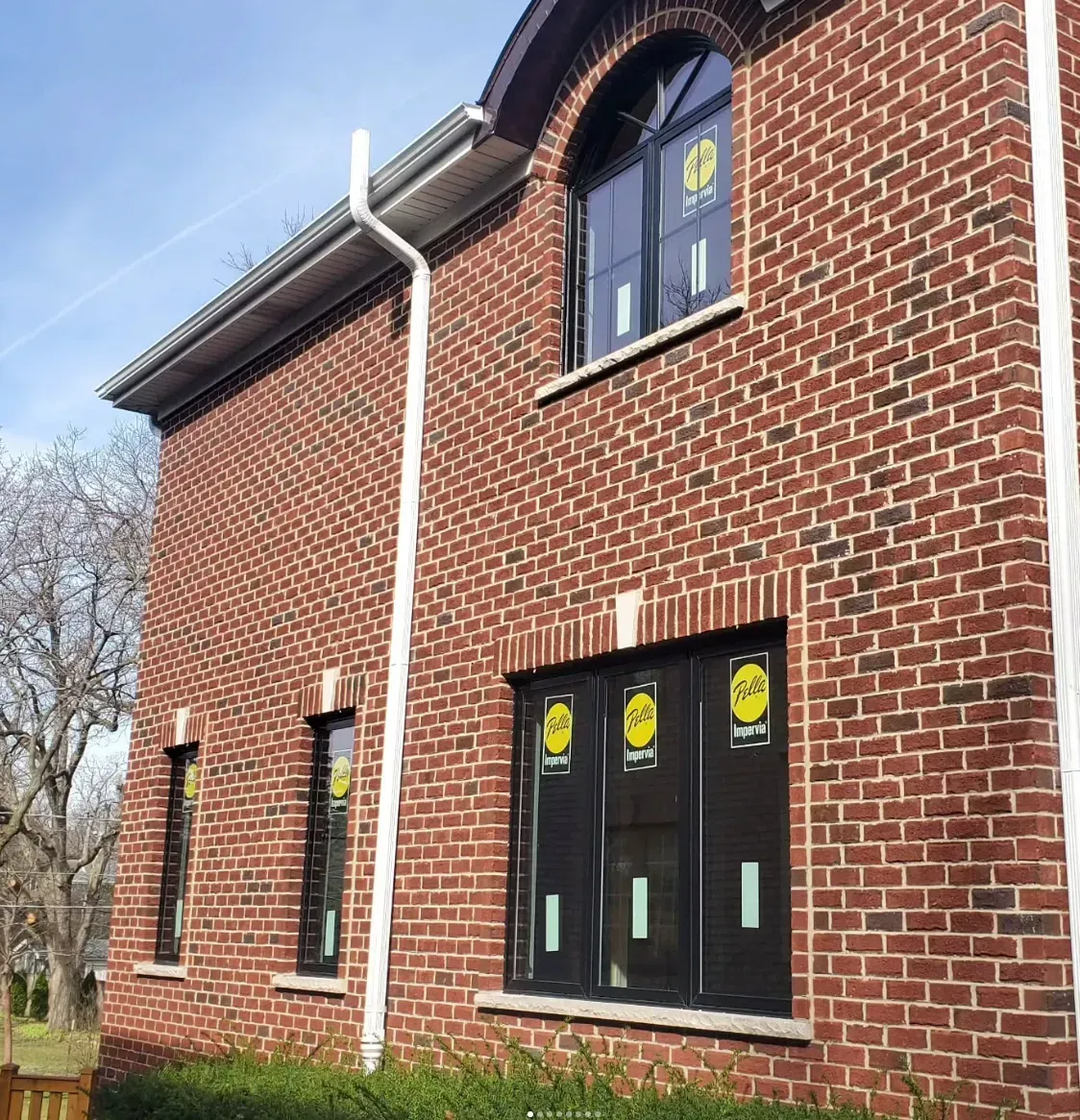 Brick house exterior with black windows and doors, viewed from a low angle.