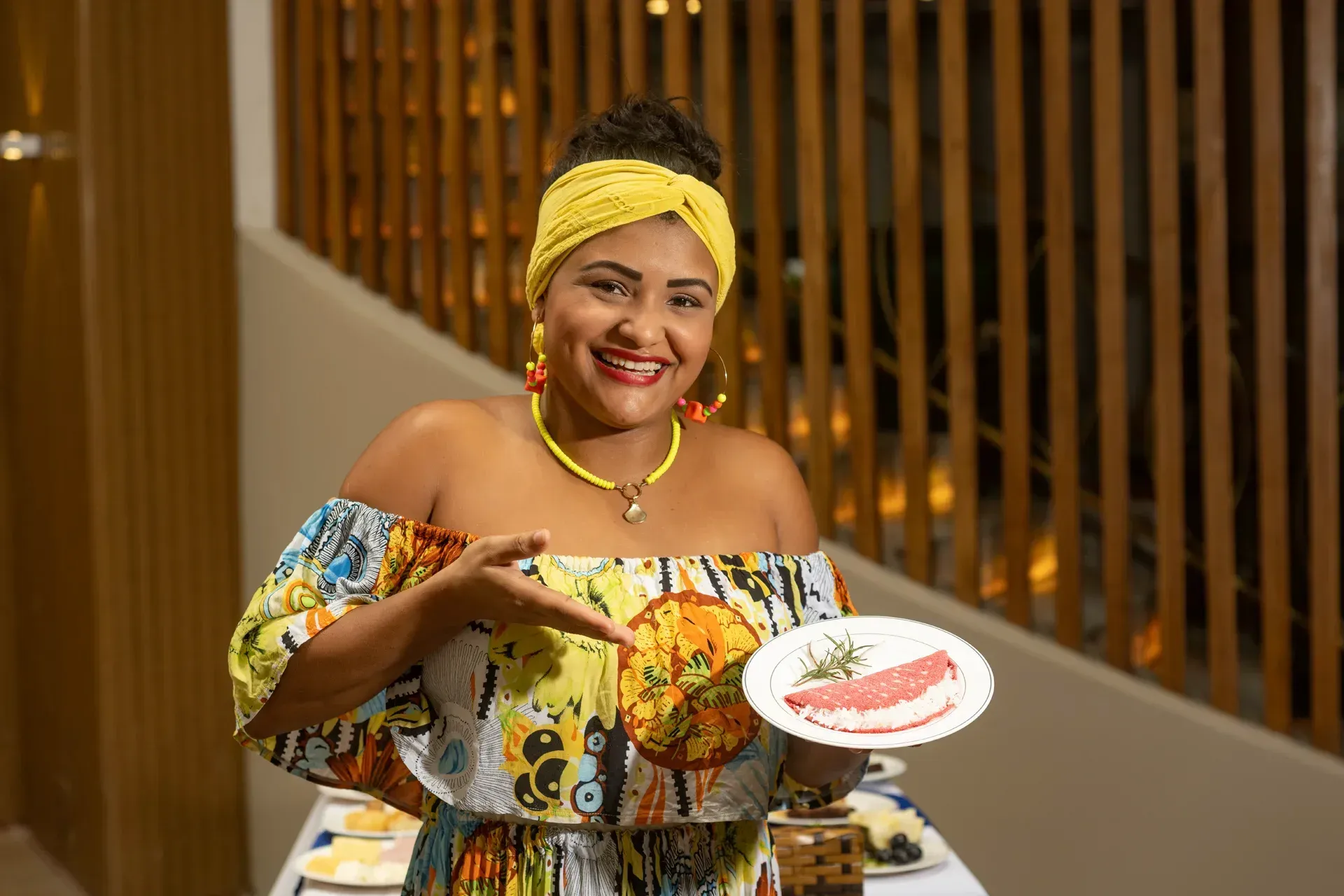 Uma mulher com um vestido colorido está segurando um prato de comida.