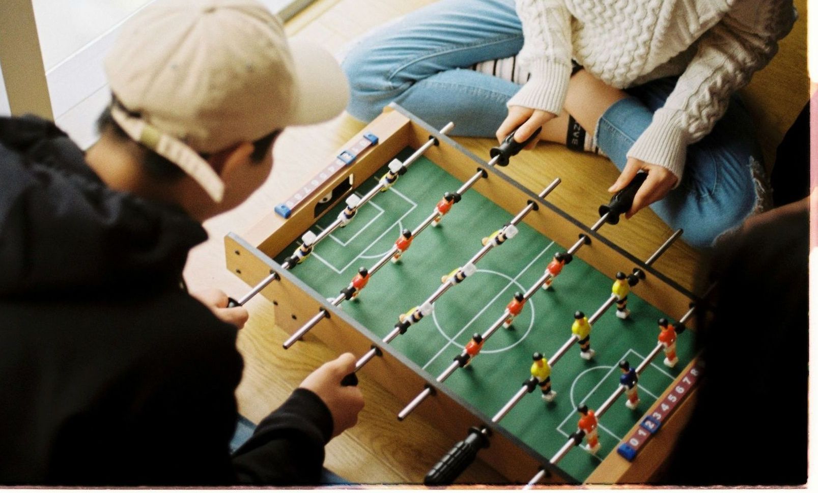 A group of people are playing a game of foosball on a table.