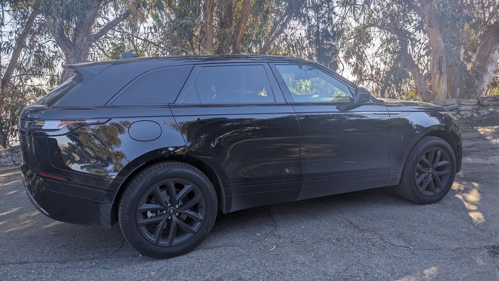 Black SUV parked on a gravel roadside with trees in the background