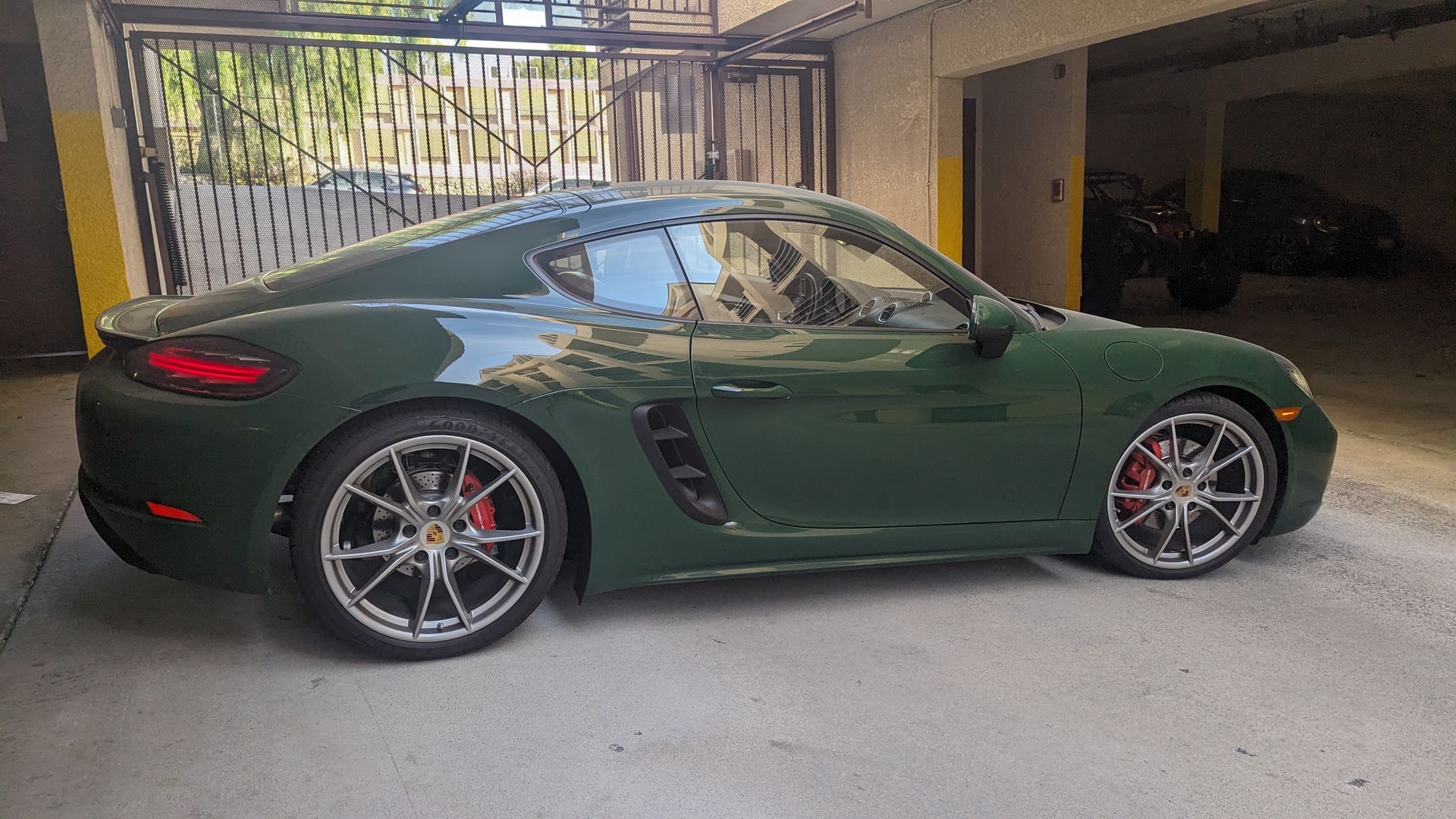 Dark green sports coupe parked in a garage, side view with red brake calipers.
