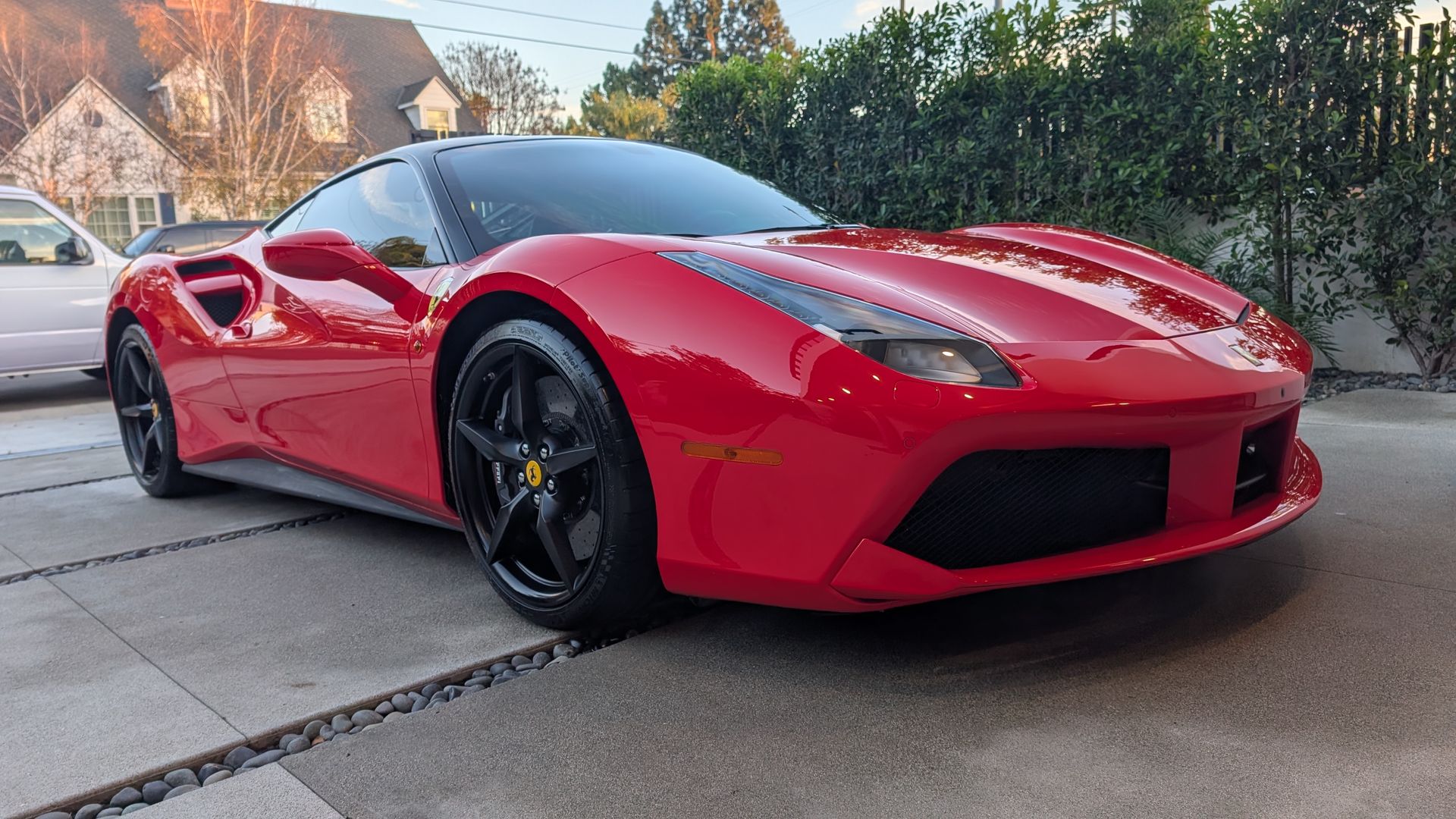 Red sports car parked on a driveway in a suburban neighborhood