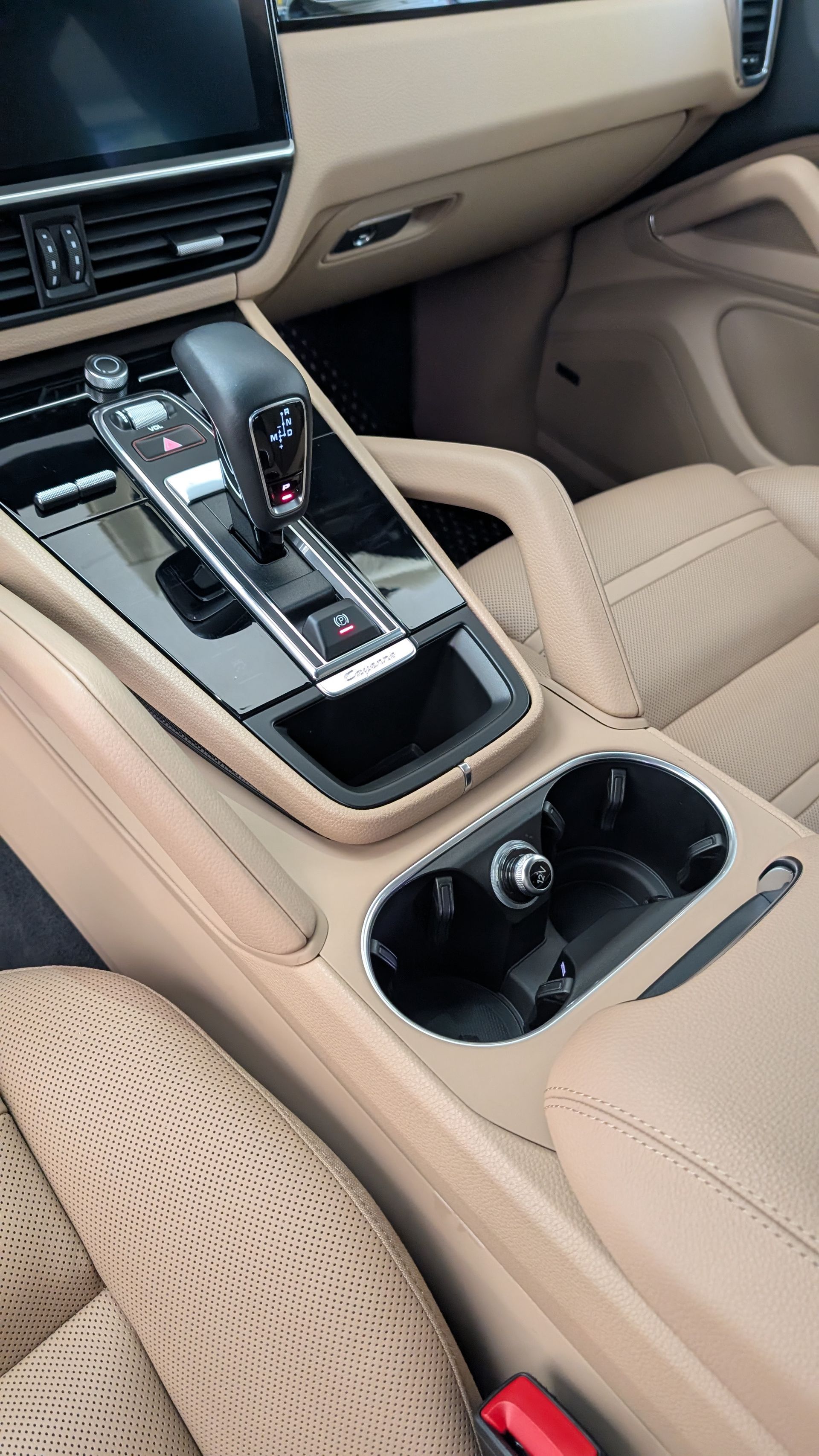 Beige luxury car interior with center console, gear selector, cup holders, and tan leather seats