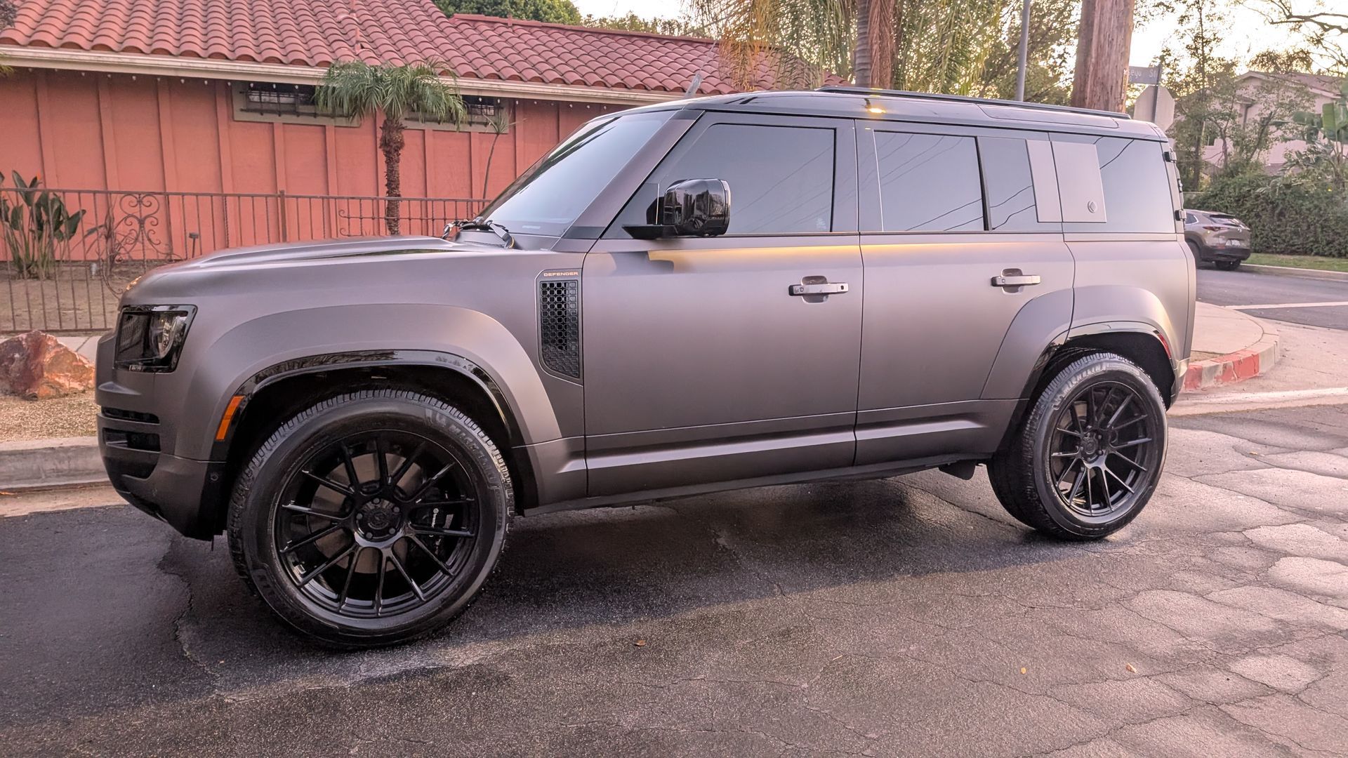 Gray SUV parked on a street beside a wall, shown in side view.