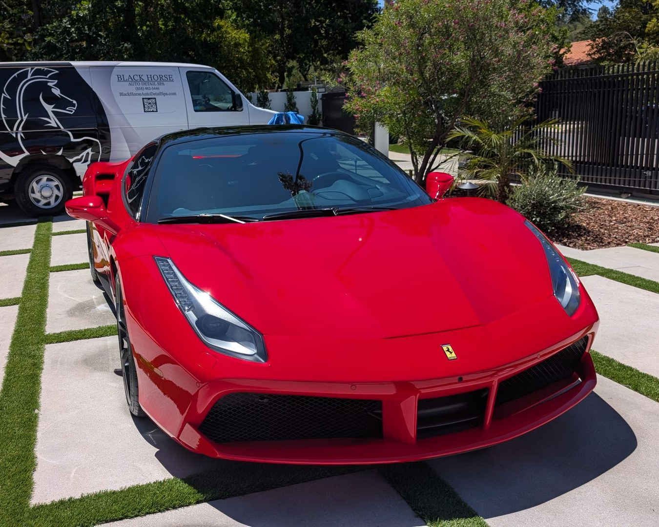 Red Ferrari convertible parked in a driveway on a sunny day