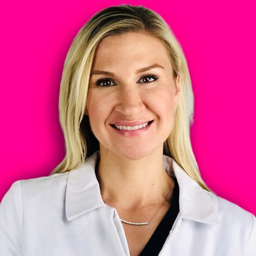 A smiling professional with blonde hair, wearing a white lab coat and a delicate necklace against a bright pink background.