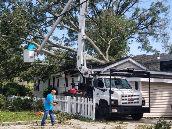 A man is standing in front of a house next to a tree cutting truck.