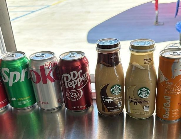 Assorted beverages in cans and bottles: Sprite, Coca-Cola, Dr. Pepper, Starbucks frappuccinos, and Red Bull.