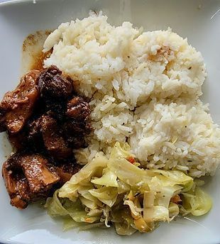 Plate with rice, stewed meat, and sauteed cabbage.
