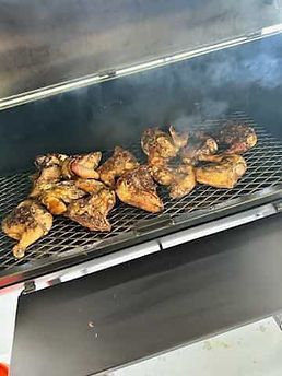 Grilled chicken pieces on a smoker. Smoke rises from the grill.