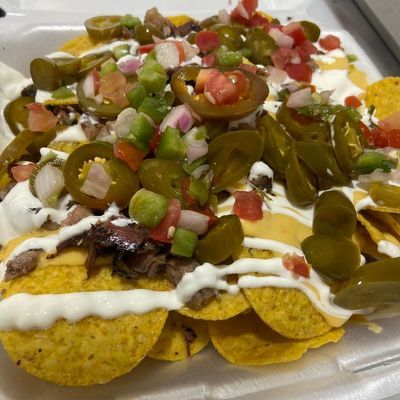 Nachos topped with cheese, jalapenos, salsa, and sour cream.