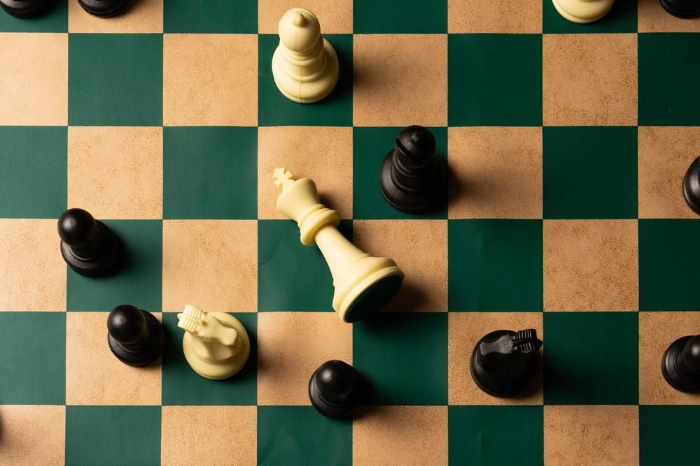 Chessboard with fallen white king and surrounding black pawns, indicating checkmate.