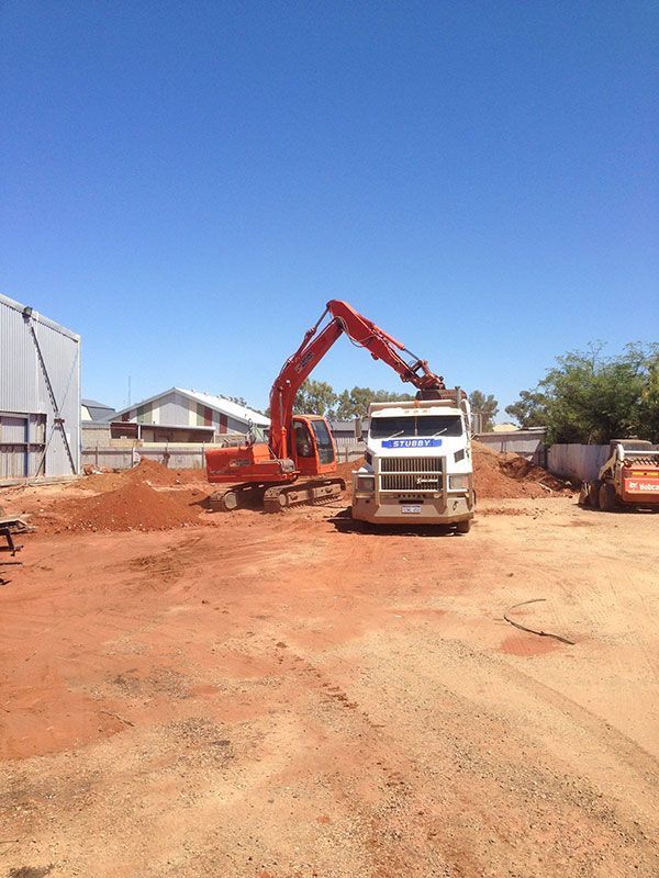 A dump truck is parked behind a fence in front of a building.