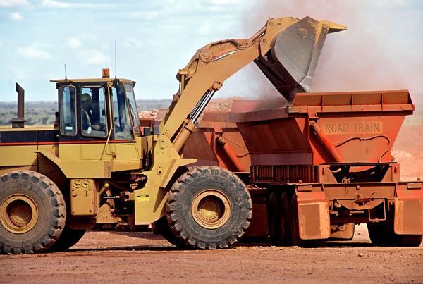 A bulldozer is loading dirt into a dumpster that says port bank