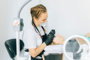 Dentist in white coat and mask working on a patient in a bright dental clinic