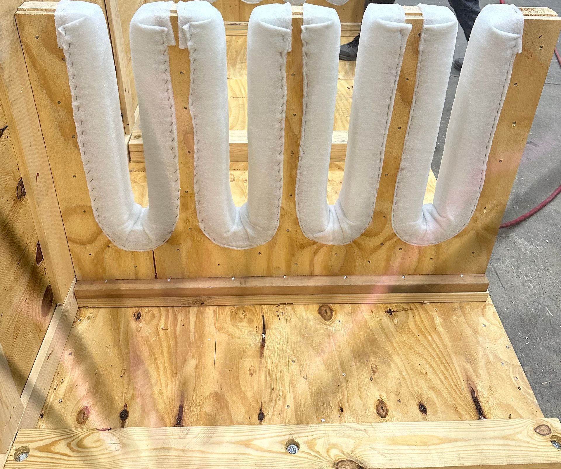 Wooden crate with white, tubular packing material secured vertically.