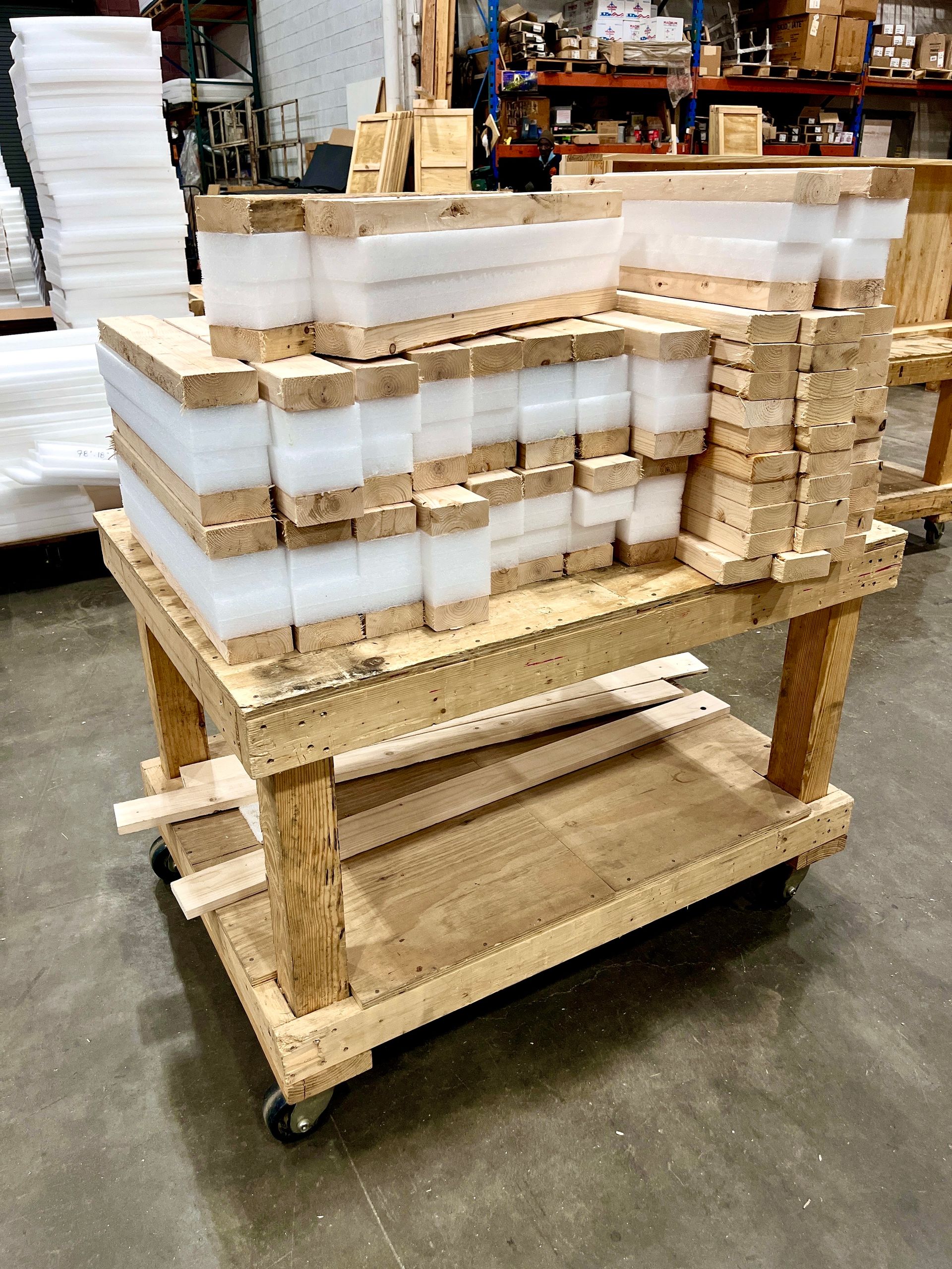 Wooden cart holding layers of wood and white foam in a warehouse.