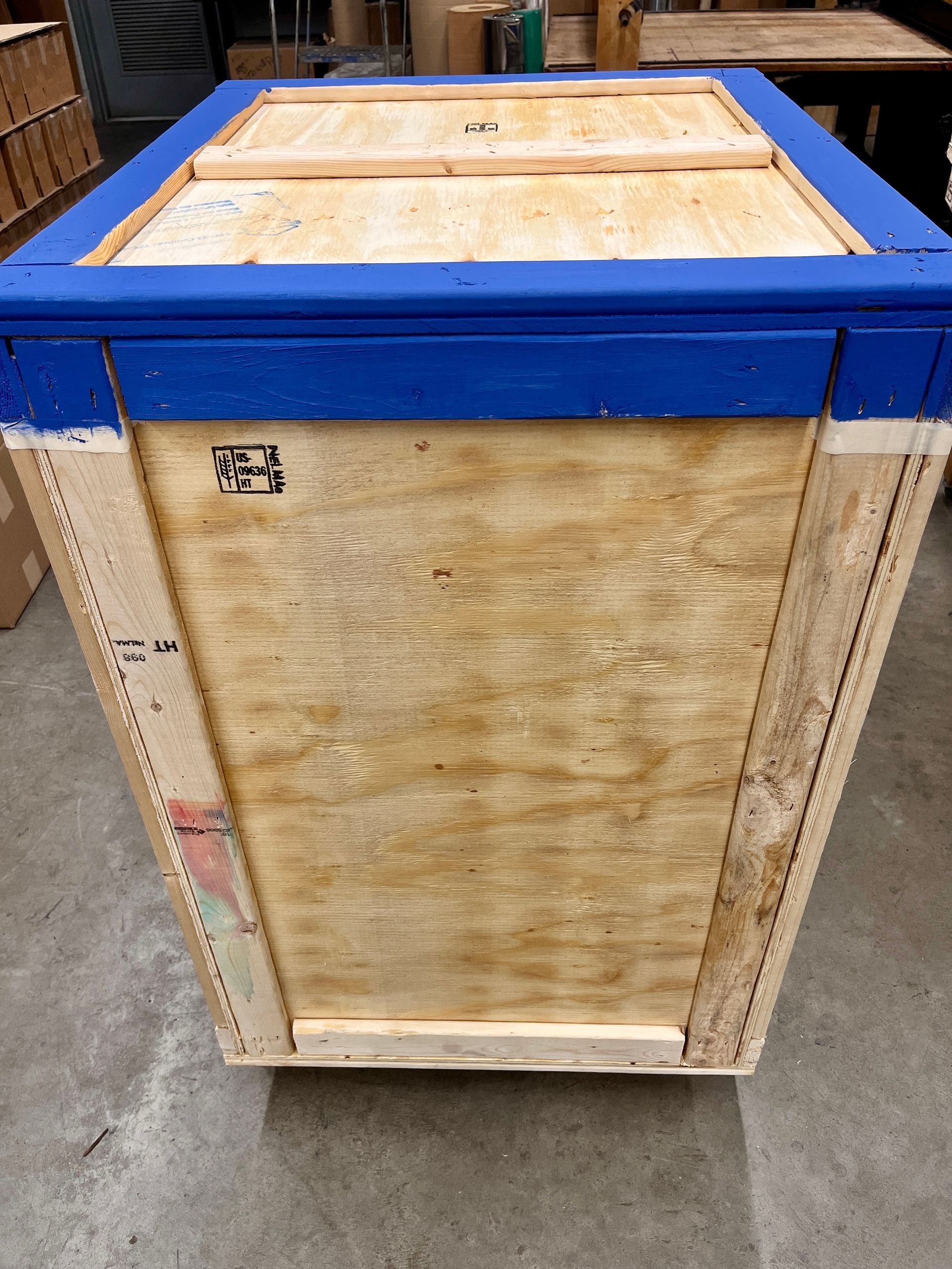 Wooden crate with blue trim, sitting on a concrete floor.