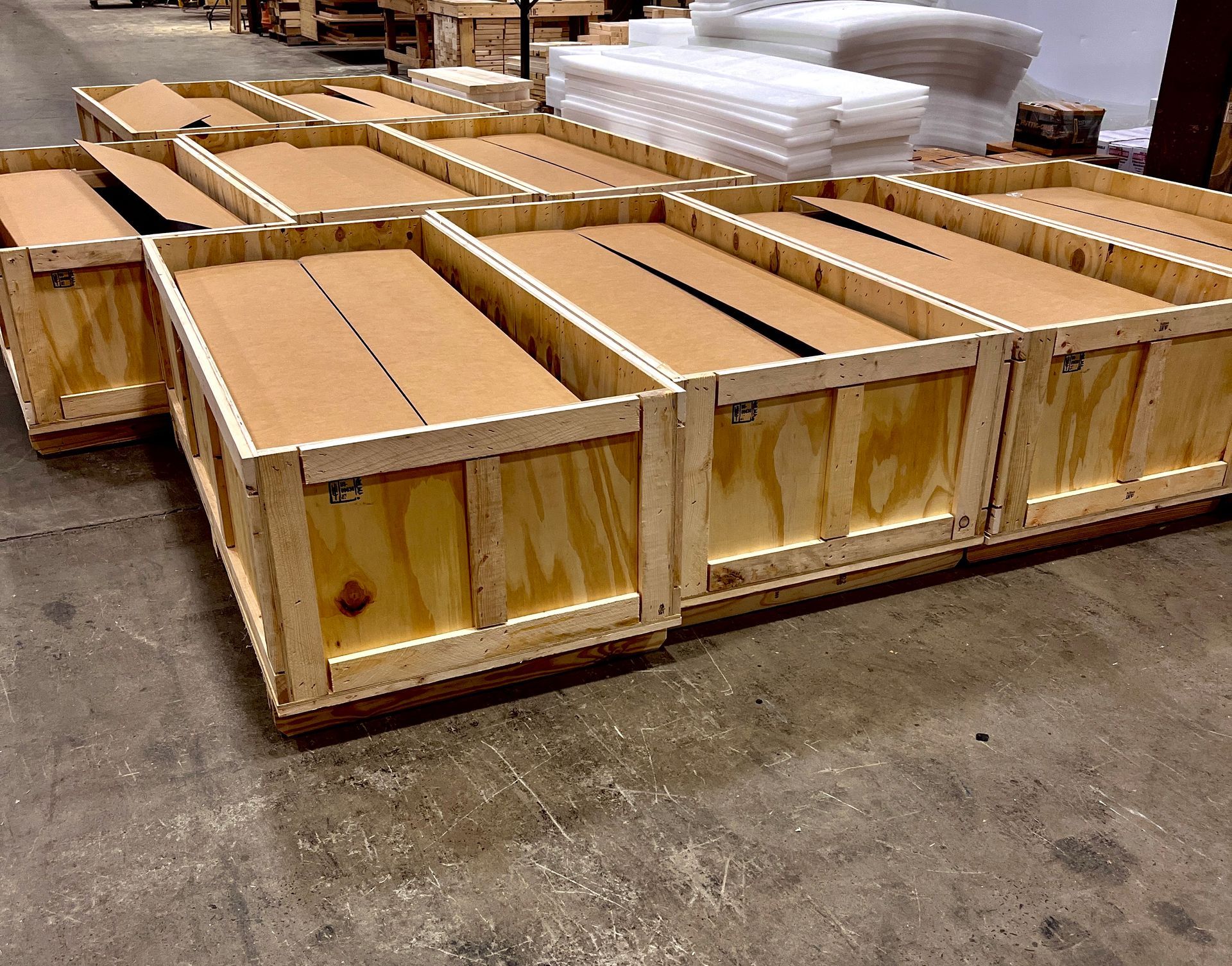 Wooden crates filled with cardboard boxes, stacked on a pallet in a warehouse.