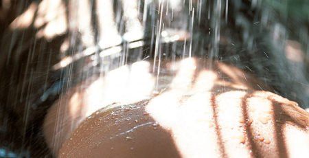 Eine Frau duscht unter einem Wasserfall.