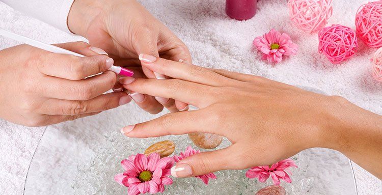 Eine Frau lässt sich in einem Nagelstudio die Nägel lackieren.