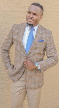 A man in a suit and tie is standing in front of a wall.