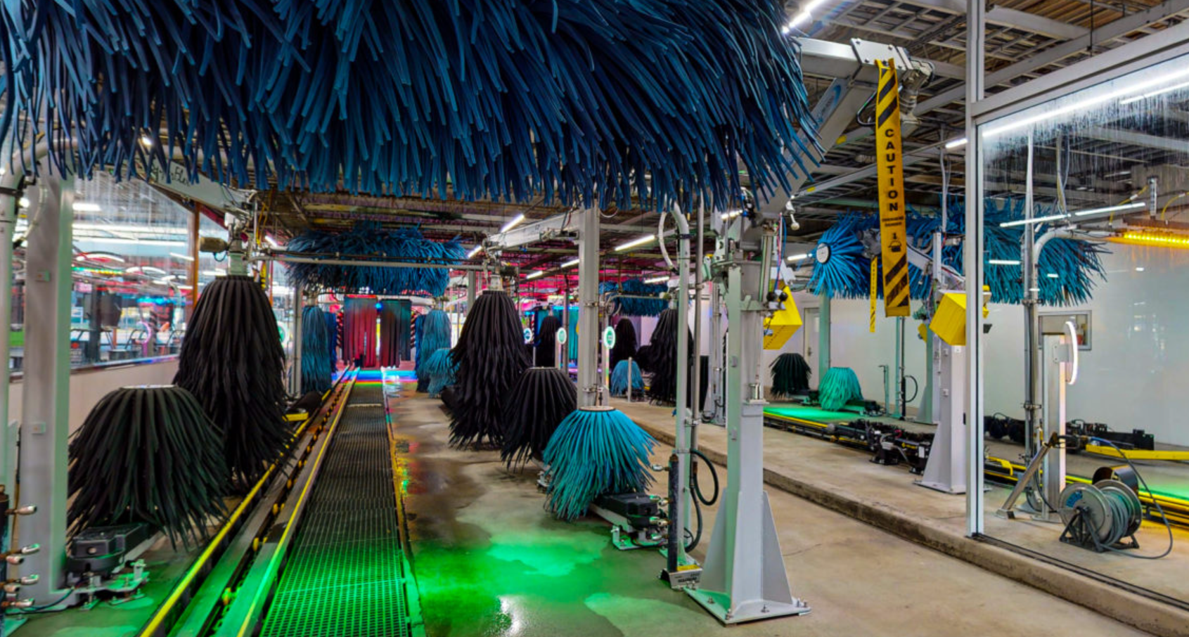 Carpeted factory conveyor line with hanging black materials and green floor lighting in an industrial workspace