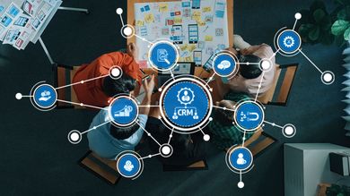 Business team around a table with a laptop and charts, overlaid with blue network and cloud icons