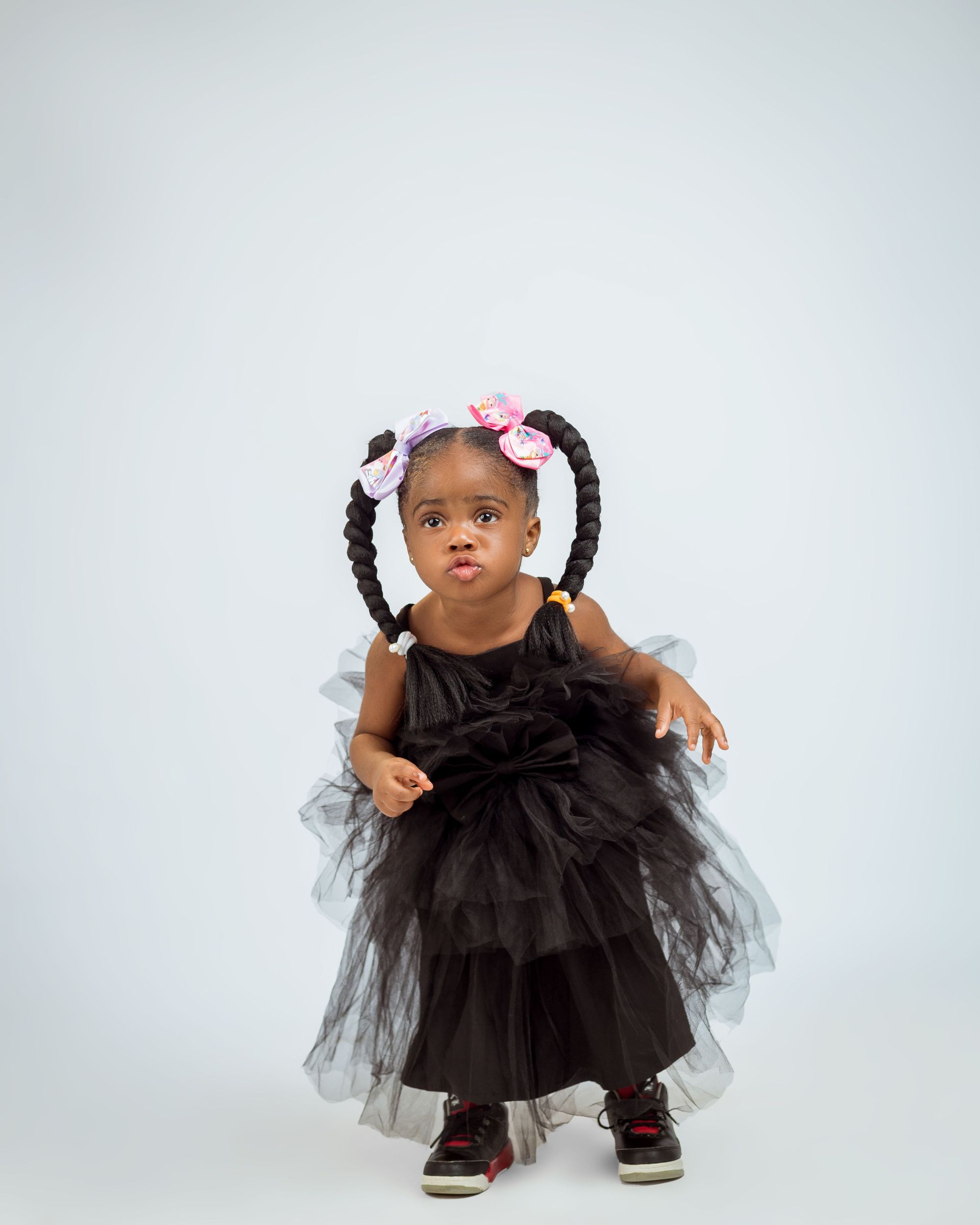 Child in a black tulle dress with floral headband standing against a light background.