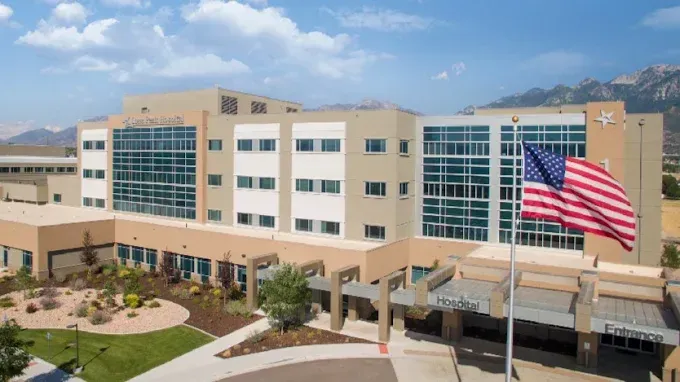 Modern hospital building with a large American flag on the facade and landscaped entrance