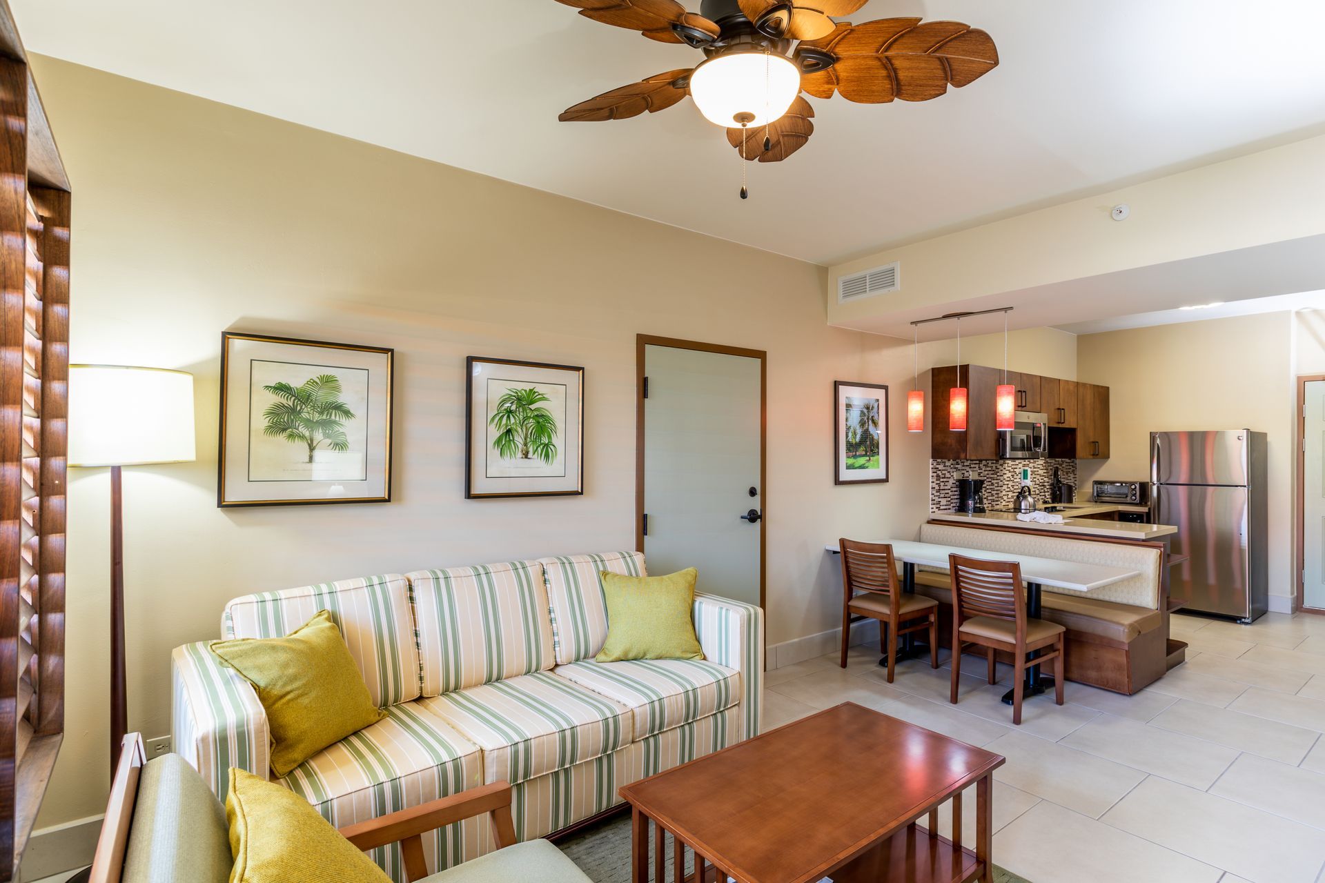 A living room with a couch , table , chairs and a ceiling fan.