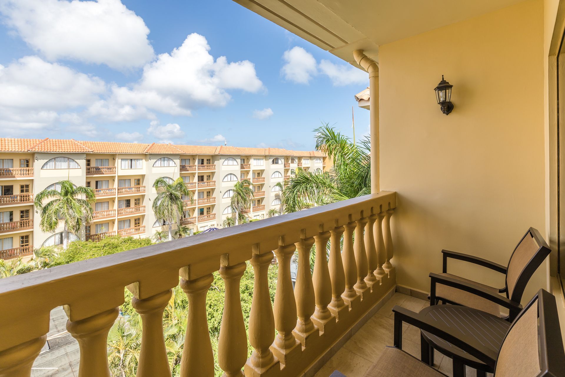 A balcony with two chairs and a table with a view of a hotel.