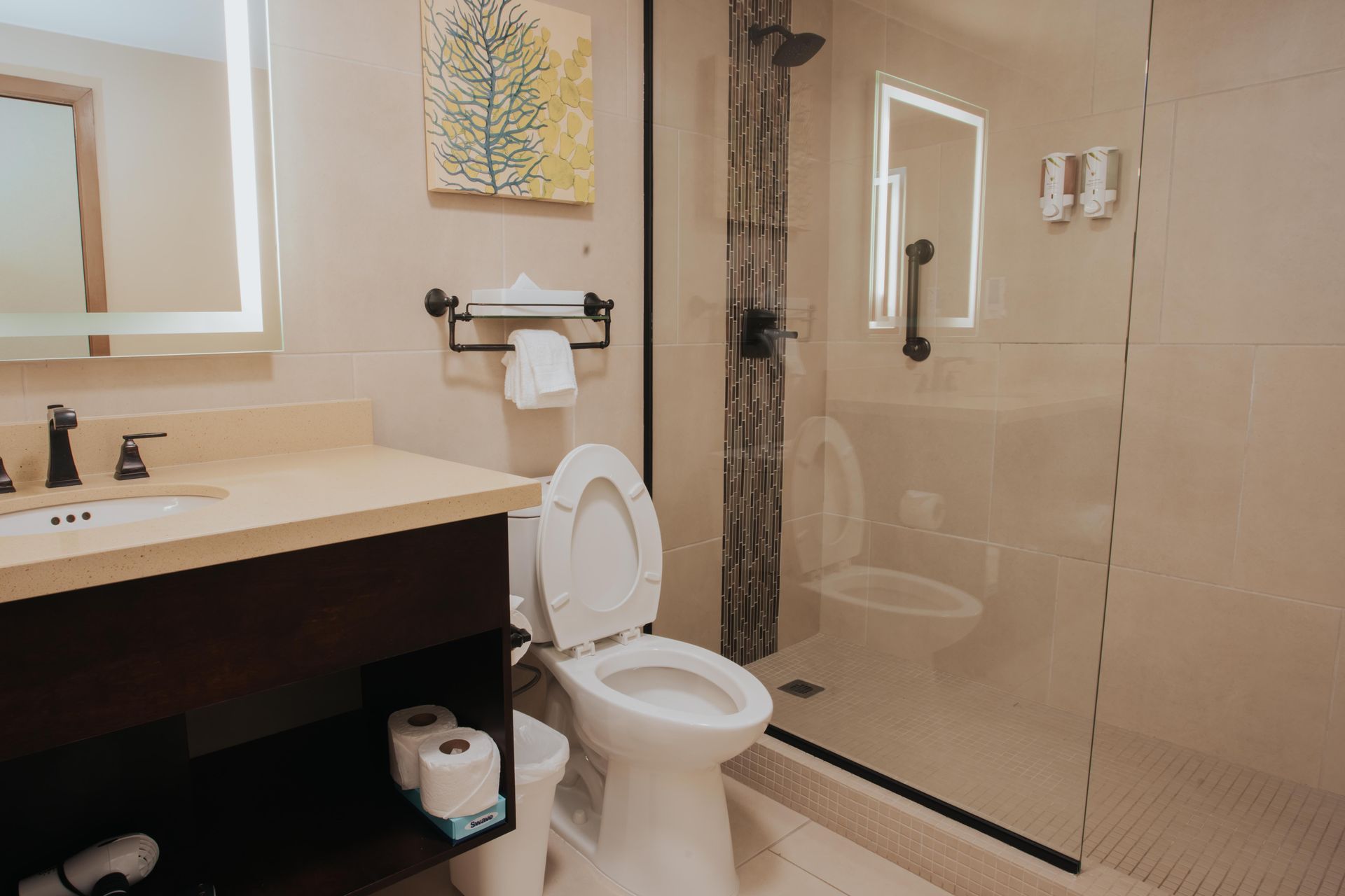 A bathroom with a toilet , sink , mirror and walk in shower.