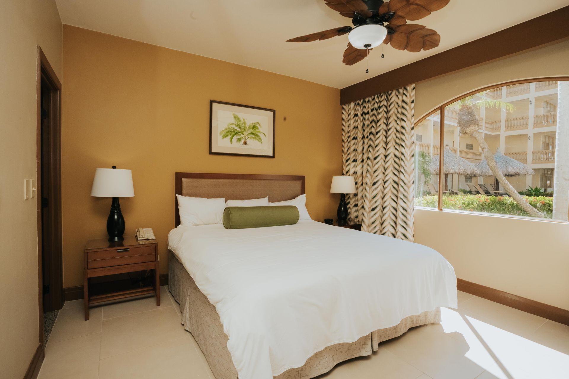 A hotel room with a king size bed and a ceiling fan.